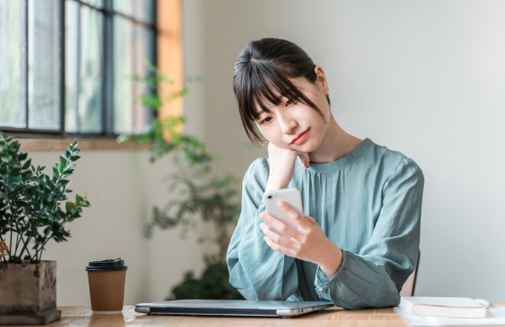 スマホを見て悩んでいる女性